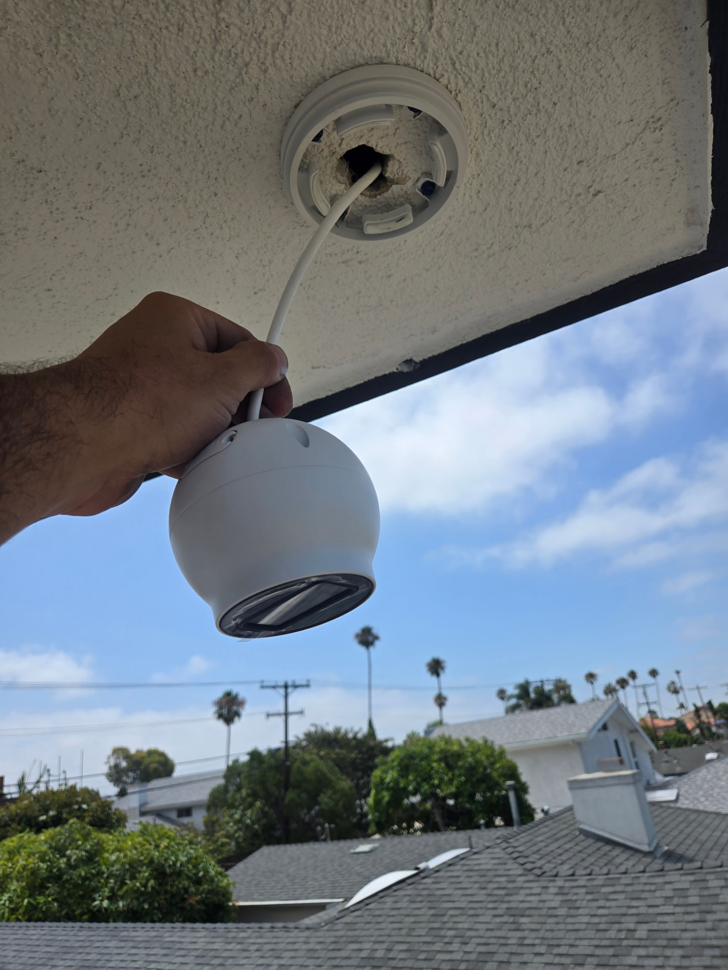 Technician lowering a dome camera from its eave mount during a maintenance visit