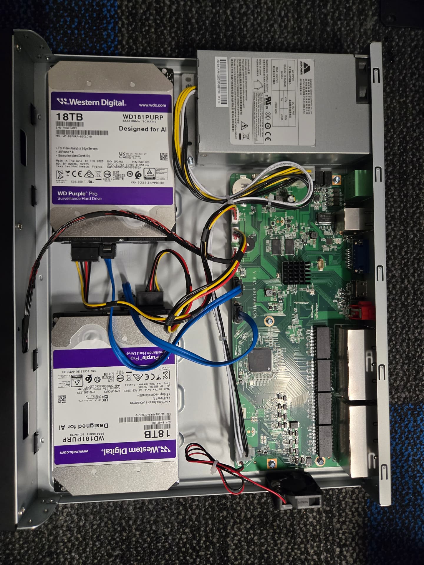 Opened network video recorder showing two surveillance-rated hard drives, the power supply and the main board